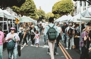 people walking around a farmers' market in the city