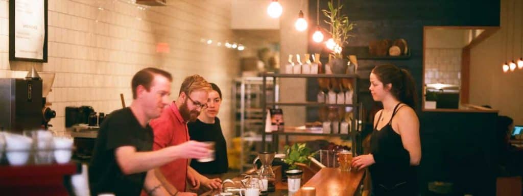 baristas and customer in front of coffee shop