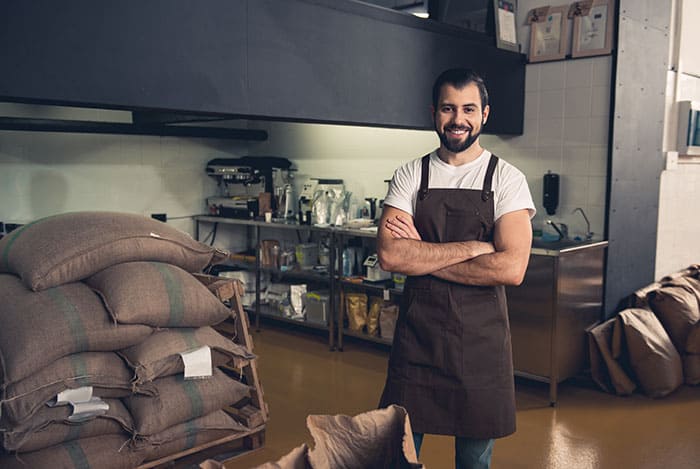 man standing next to coffee bean sacs